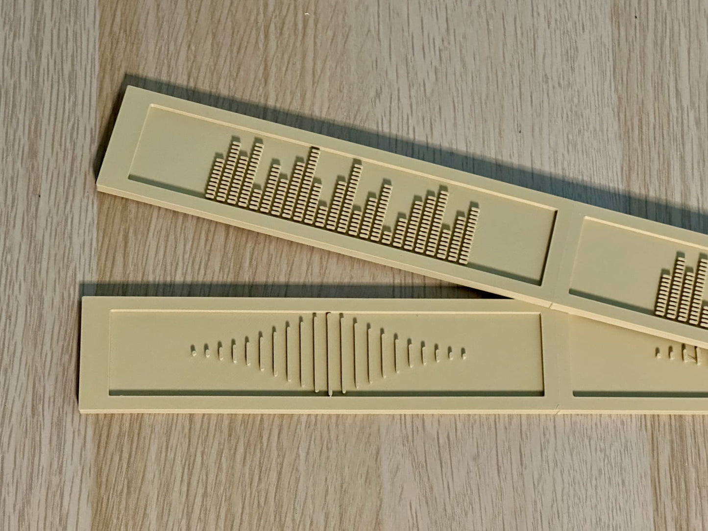 Beige deluxe backspacers with the EQ and Sound Wave designs displayed on top of a white oak IKEA Kallax shelf. 
