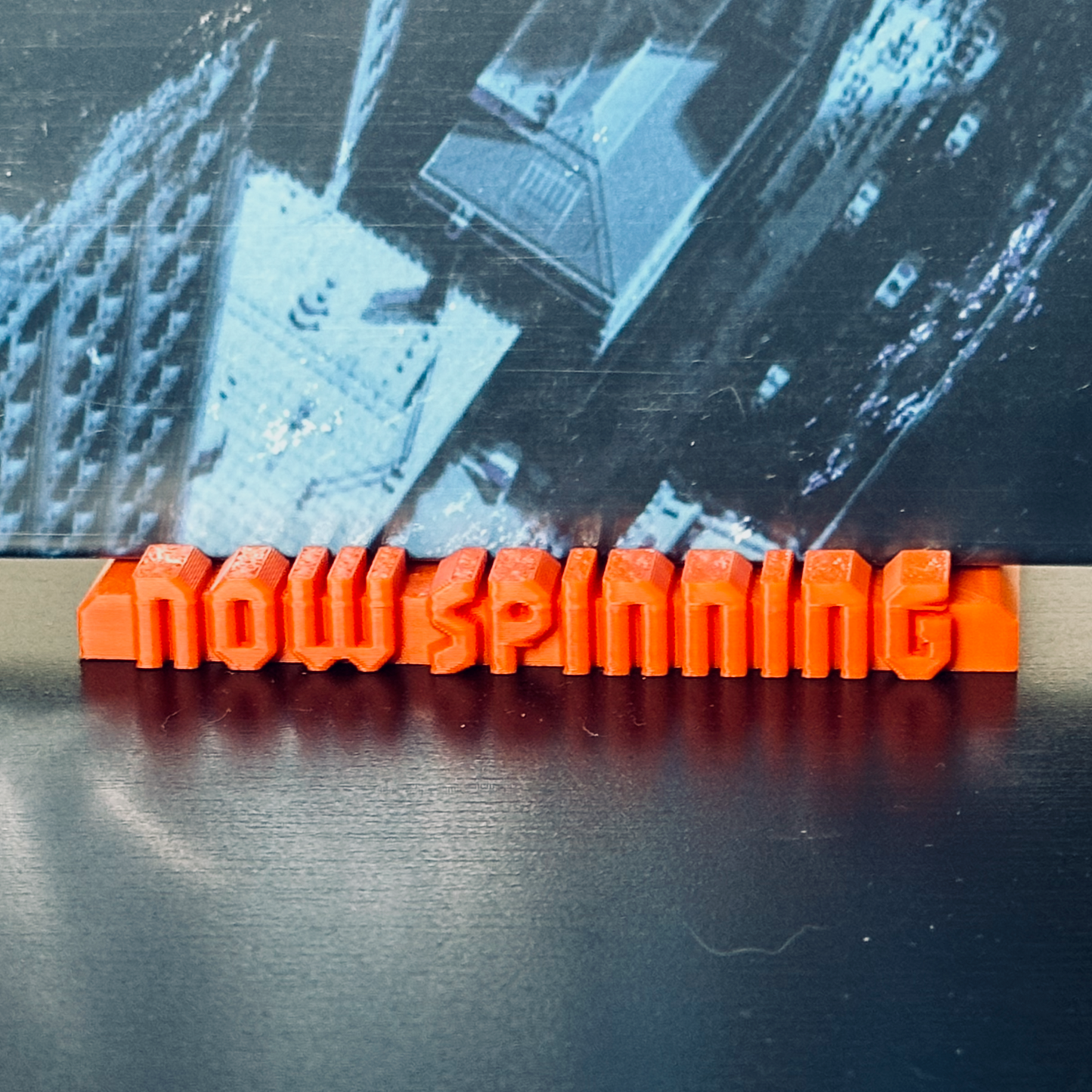 Closeup of the orange "Now Spinning" display stand with a record in place.