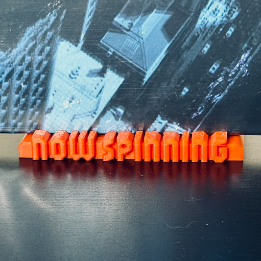 Closeup of the orange "Now Spinning" display stand with a record in place.