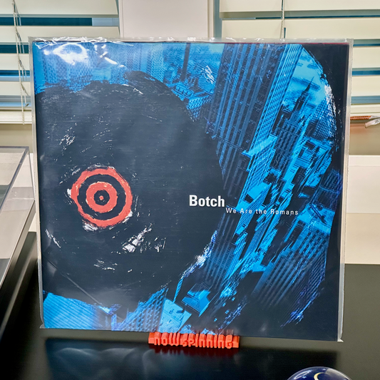 Medium view of the orange "Now Spinning" display stand with a record in place next to a turntable.