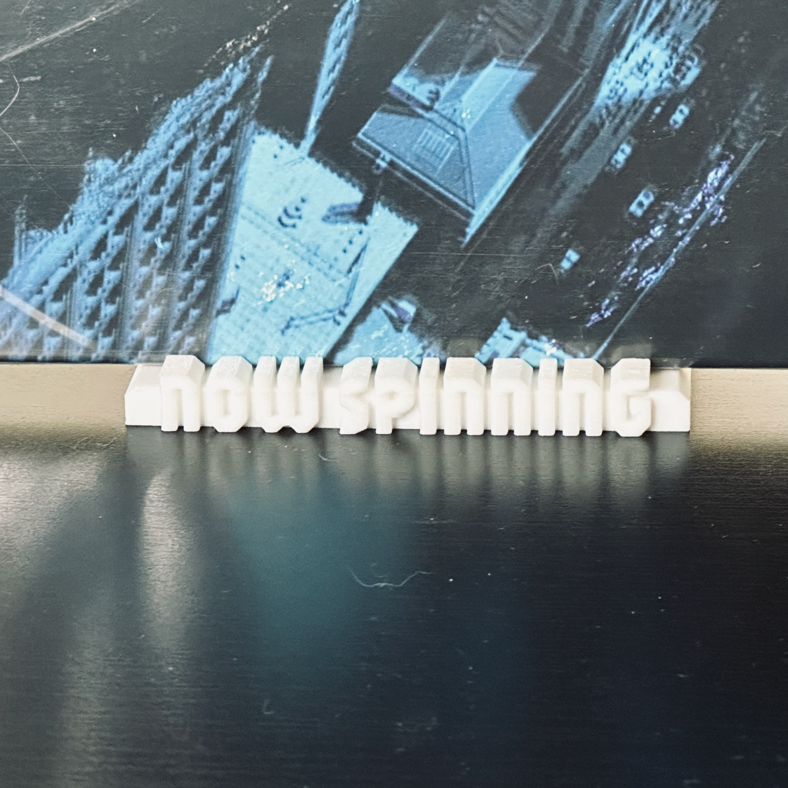 Closeup of the white "Now Spinning" display stand with a record in place.