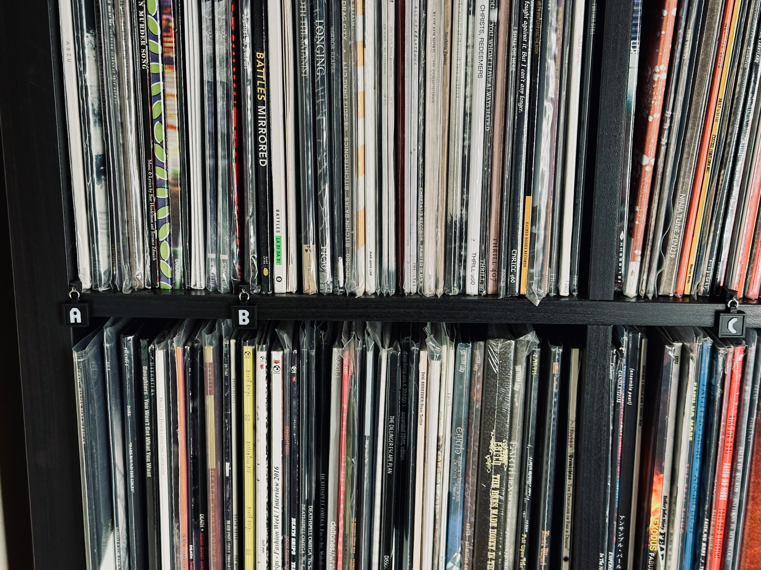 A shelf holding numerous records neatly aligned in the front and labeled with letter shelf tags