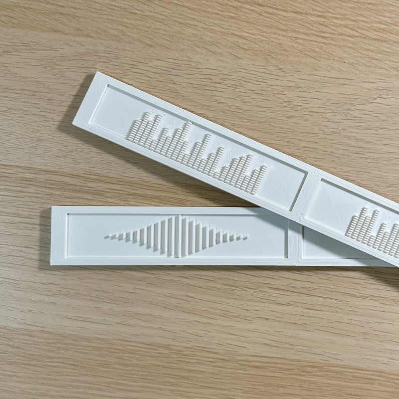 White deluxe backspacers with the EQ and Sound Wave designs displayed on top of a white oak IKEA Kallax shelf. 