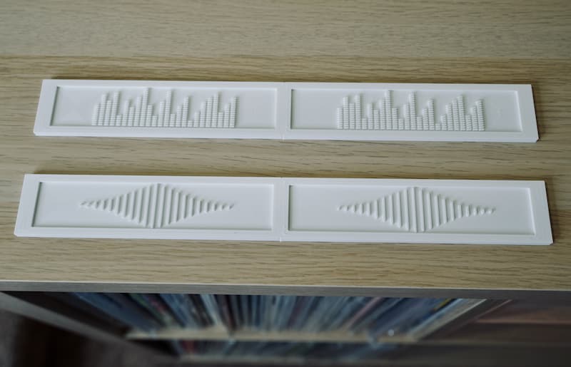 White Deluxe Backspacers with the EQ and Soundwave patterns displayed on top of a white oak Ikea shelf